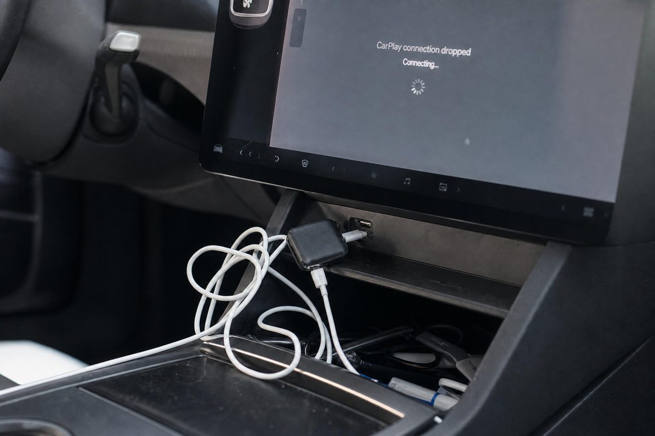 A cheap generic CarPlay dongle with a tangled cable and a dropped connection on the Tesla screen